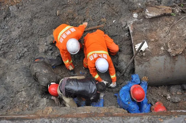 Rescuers use their bare hands to dig through mounds of earth to save construction workers buried in Suizhou, Hubei Province, China, May 9, 2016. (Photo by Reuters/Stringer)