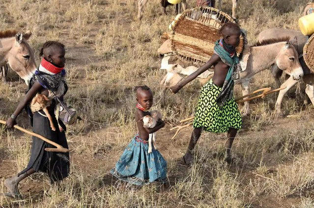 Girls hold little goats as Turkana people migrate in order to find water and grazing land for cattle in Ilemi Triangle, Kenya, July 23, 2019. (Photo by Goran Tomasevic/Reuters)
