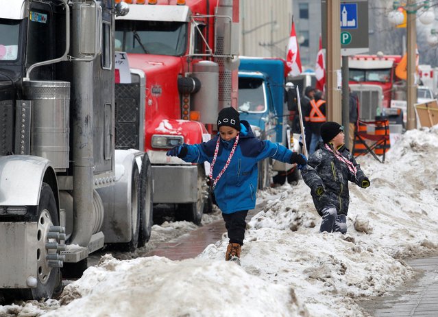 Children play on snow banks as truckers and their supporters continue to protest against the coronavirus disease (COVID-19) vaccine mandates, in Ottawa, Ontario, Canada, February 8, 2022. (Photo by Patrick Doyle/Reuters)