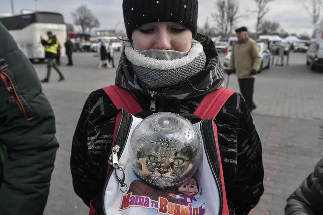 A girl carries her cat in a backpack as she waits to board a bus transporting her further in Poland or abroad from the temporary shelter for refugees located in a former shopping center between the Ukrainian border and the Polish city of Przemysl, in Poland, on March 8, 2022. More than two million people have fled Ukraine since Russia launched its full-scale invasion less than two weeks ago, the United Nations said on March 8, 2022. Poland alone has received nearly half of all those fleeing Ukraine, with figures dated March 8, 2022 showing that 1,2 million had crossed into the country in the past 13 days. (Photo by Louisa Gouliamaki/AFP Photo)
