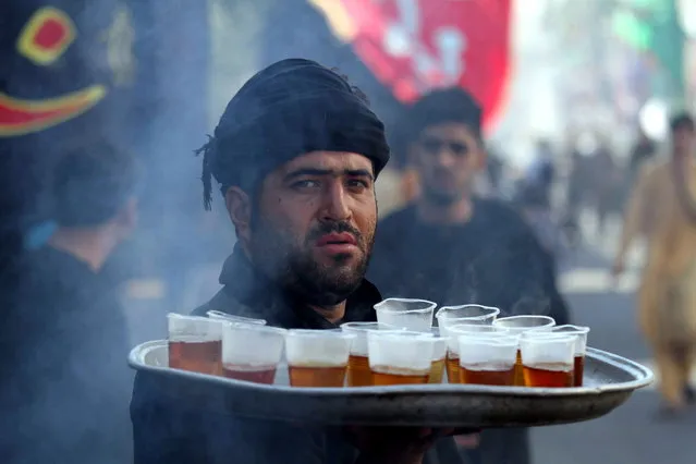 An Afghan Shiite Muslim serves drinks to mourners at an Ashura mourning procession during the Islamic sacred month of Muharram in Herat, Afghanistan, 10 September 2019. Shiite Muslims are observing the holy month of Muharram, the climax of which is the Ashura festival that commemorates the martyrdom of Imam Hussein, a grandson of the Prophet Mohammed, in the Iraqi city of Karbala in the seventh century. (Photo by Jalil Rezayee/EPA/EFE)