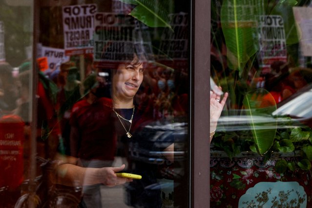 A woman looks out a window as demonstrators and members of the The Coalition to March on the RNC hold a rally, on the first day of the Republican National Convention (RNC) in Milwaukee, Wisconsin on July 15, 2024. (Photo by Evelyn Hockstein/Reuters)