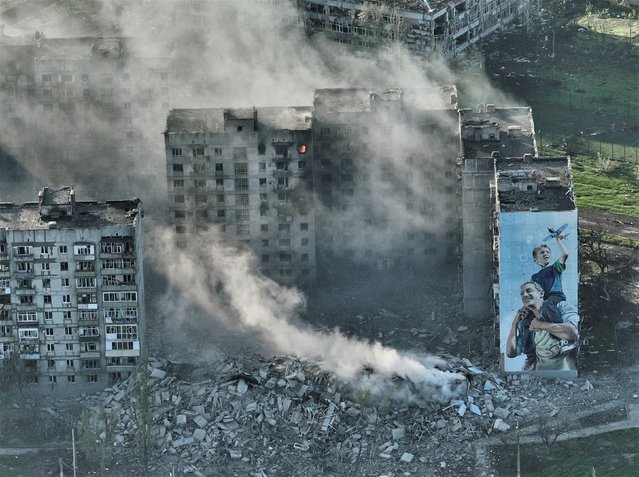 Smoke rises from a building in Bakhmut, the site of the heaviest battles with the Russian troops in the Donetsk region, Ukraine, Wednesday, April 26, 2023. (Photo by Libkos/AP Photo)