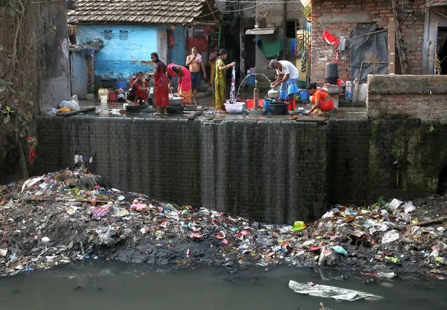 Residents fill water containers and wash their clothes from municipal water pipes alongside a polluted water channel at a slum in Kolkata, India, March 22, 2022. (Photo by Rupak De Chowdhuri/Reuters)