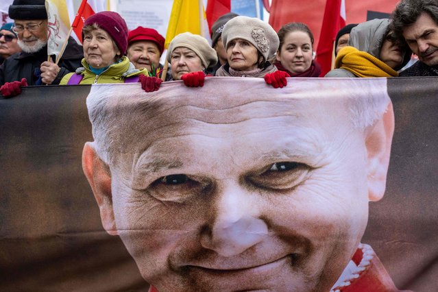 Supporters march to defend the memory of late former Polish-born Pope John Paul II with a large banner showing the former pope on the 18th anniversary of his death, in Warsaw, Poland on April 2, 2023. The late Polish pope John Paul II knew about child abuse in Poland's Catholic church years before becoming pontiff and helped cover it up, according to reports of private broadcaster TVN released at the beginning of March 2023. Michal Gutowski, the investigator behind the broadcast, said that Karol Wojtyla, as he then was, knew of cases of paedophile priests within the church while still a cardinal in Krakow. (Photo by Wojtek Radwański/AFP Photo)