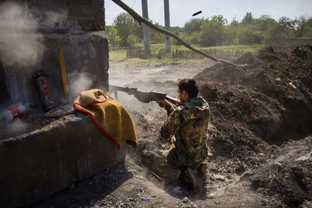 A pro-Russian militant opens fire as a test from an anti-tank weapon preparing to fight against Ukrainian government troops at a checkpoint blocking the major highway which links Kharkiv, outside  Slovyansk, eastern Ukraine, on May 18, 2014. (Photo by Alexander Zemlianichenko/Associated Press)