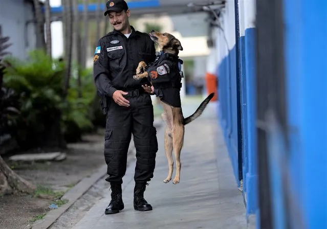 Police Cpl. Cristiano de Oliveira plays with rescue dog “Corporal Oliveira”, at the 17 Military Police Battalion's station, in Rio de Janeiro, Brazil, Thursday, April 7, 2022. “I gave him food, water. It took a while for him to get used to me”, said Oliveira, the officer who took the dog under his wing and later gave him his name. (Photo by Silvia Izquierdo/AP Photo)