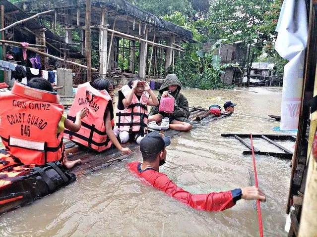 This handout photo taken on April 12, 2022 and received from the Philippine Coast Guard shows coast guard personnel evacuating local residents from their flooded homes on a makeshift raft in the town of Panitan, Capiz province as heavy rains brought on by Tropical Storm Megi inundated the area. (Photo by Handout/Philippine Coast Guard (PCG)/AFP Photo)