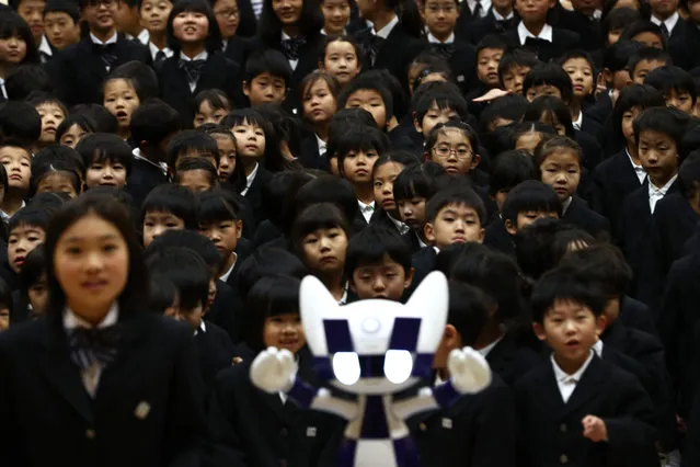 Schoolchildren pose for a picture with Tokyo 2020 Olympic Games' robot-type mascot Miraitowa during a ceremony at Hoyonomori elementary school in Tokyo on November 18, 2019. Tokyo 2020 Summer Games' mascot robots visited an elementary school, drawing cheers and laughters from children as they gave them quizzes and responded to verbal instructions. (Photo by Behrouz Mehri/AFP Photo)