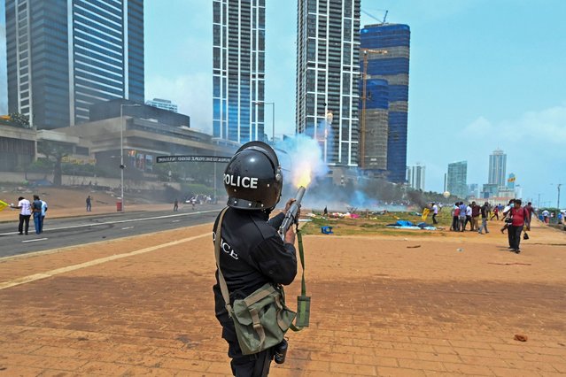A policeman fires tear gas during a clash between government supporters and demonstrators outside the President's office in Colombo on May 9, 2022. Police imposed an indefinite curfew in Sri Lanka's capital on May 9 after government supporters clashed with demonstrators demanding the resignation of President Gotabaya Rajapaksa. (Photo by Ishara S. Kodikara/AFP Photo)