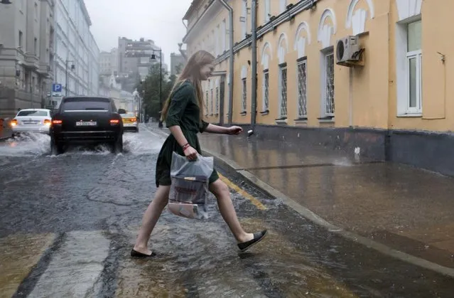 A woman crosses a flooded street in heavy rain during a thunderstorm in Moscow, Russia, Friday, June 30, 2017. A massive thunderstorm in the Moscow region has killed at least one and injured several people. (Photo by Denis Tyrin/AP Photo)