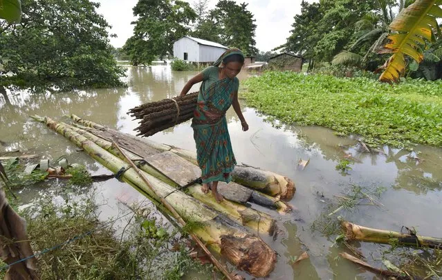 In this photograph taken on July 5, 2017, an Indian woman carries cow dung, which is used as fuel for fires, on a raft through floodwaters in Buraburi village in Morigoan district in the northeastern state of Assam. At least five people were killed and 10 missing July 11 after a massive landslide buried homes in a remote village in northeast India, a disaster management official said. An avalanche of mud and rock struck the village after weeks of heavy rain in Papum Pare district in the Himalayan state of Arunachal Pradesh along the border with China. (Photo by Biju Boro/AFP Photo)