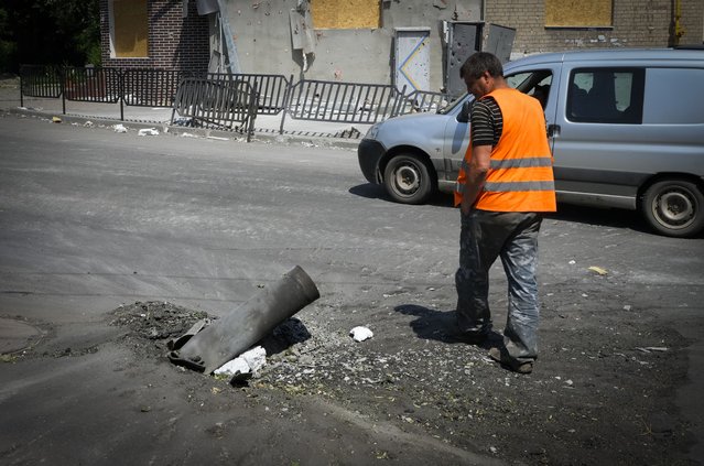 A municipal worker passes by a fragment of a Russian rocket following night shelling in the town of Bakhmut, Donetsk region, Ukraine, Monday, June 13, 2022. (Photo by Efrem Lukatsky/AP Photo)