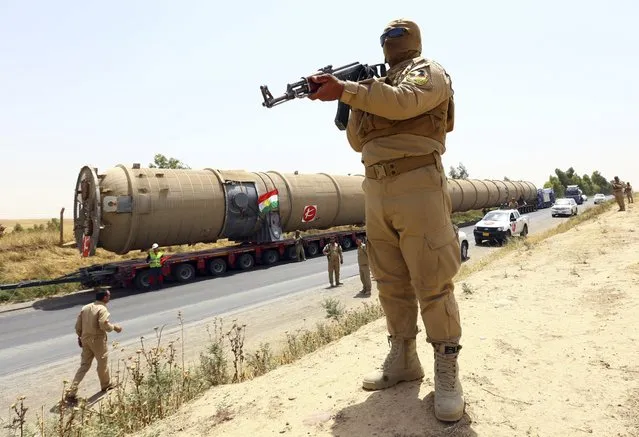 A member of the Kurdish security forces takes up position with his weapon as he guards a section of an oil refinery, which is being brought on a truck to Kalak refinery in the outskirts of Arbil, in Iraq's Kurdistan region, July 14, 2014. (Photo by Reuters/Stringer)