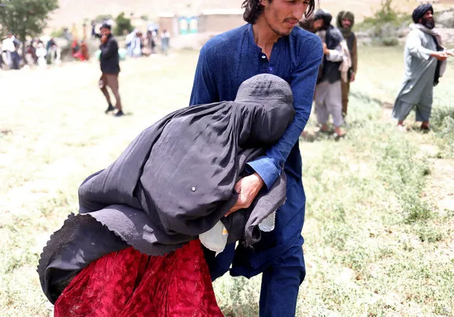 An Afghan woman is helped to reach an evacuation helicopter after she lost some of her relatives in an earthquake in Gayan, Afghanistan, June 23, 2022. (Photo by Ali Khara/Reuters)