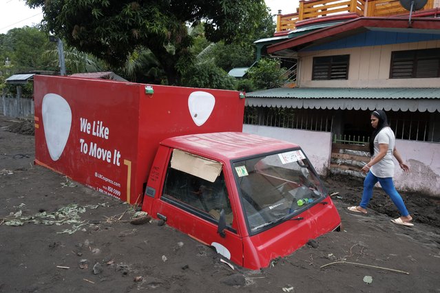 A resident walks beside a truck buried by volcanic mud that flowed down from Mayon volcano after heavy rains caused by Tropical Storm Trami hit Guinobatan town, Albay province, Philippines on Wednesday October 23, 2024. (Photo by John Michael Magdasoc/AP Photo)