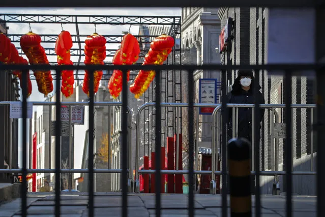 A security guard wearing a protective face mask stands near barricades placed at a quiet main Qianmen Street, a popular tourist spot, in Beijing, Sunday, February 16, 2020. (Photo by Andy Wong/AP Photo)
