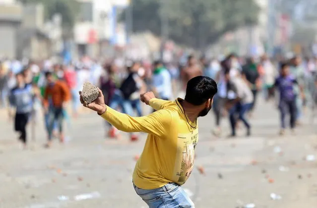 A man supporting a new citizenship law throws a stone at those who are opposing the law, during a clash in New Delhi, India, February 24, 2020. (Photo by Danish Siddiqui/Reuters)