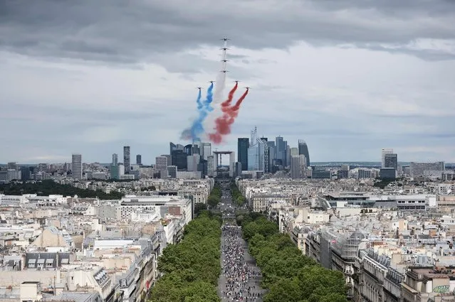 Alphajet aircrafts from the French elite acrobatic flying team Patrouille de France (PAF) release smoke in the colours of the French national flag above the La Defense business district during the annual Bastille Day military parade on the Champs-Elysees avenue in Paris on July 14, 2016. France holds annual Bastille Day military parade with troops from Australia and New Zealand as special guests among the 3,000 soldiers who will march up the Champs-Elysees avenue. They will be accompanied by 200 vehicles with 85 aircraft flying overhead. (Photo by Stephane De Sakutin/AFP Photo)