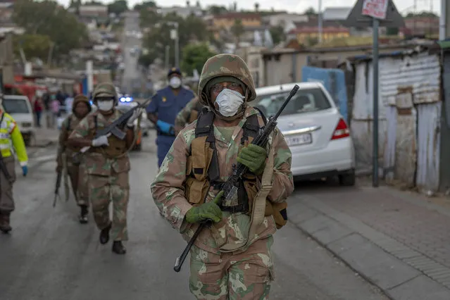 South African National Defense Forces patrol the densely populated Alexandra township east of Johannesburg Friday, March 27, 2020. South Africa went into a nationwide lockdown for 21 days in an effort to mitigate the spread to the coronavirus, but in Alexandra, many people were gathering in the streets disregarding the lockdown. (Photo by Jerome Delay/AP Photo)