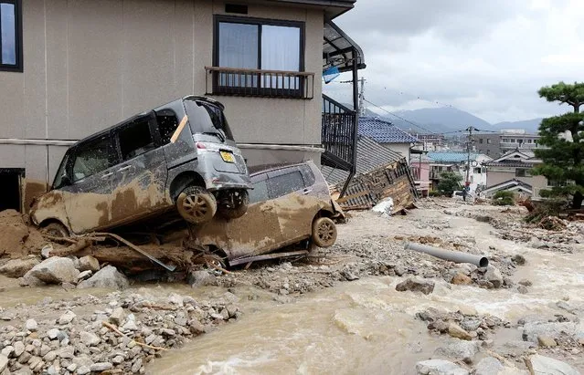 Cars damaged by a landslide lie in mud and debris after heavy rains hit the city of Hiroshima, western Japan, on August 20, 2014. (Photo by AFP Photo/Jiji Press)