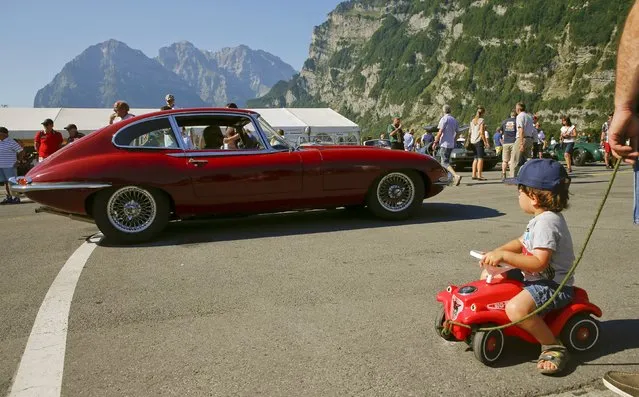 A boy looks at a vintage Jaguar E-Type sports car driving past during the British Car Meeting 2015 in the village of Mollis, east of Zurich, August 30, 2015. (Photo by Arnd Wiegmann/Reuters)