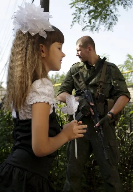 A schoolgirl walks past a member of the self-proclaimed Donetsk People's Republic forces on the start of the new school year in Donetsk, Ukraine, September 1, 2015. (Photo by Alexander Ermochenko/Reuters)