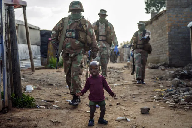 South African National Defense Forces patrol the Sjwetla informal settlement after pushing back residents into their homes, on the outskirts of the Alexandra township in Johannesburg, Monday, April 20, 2020. The residents were protesting the lack of food. Many have lost their income as South Africa is under a strict five-week lockdown in a effort to fight the coronavirus pandemic. (Photo by Jerome Delay/AP Photo)