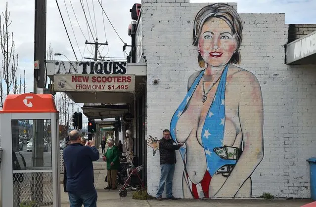 A man poses for a photograph in front of a mural of Democrat US presidential nominee Hillary Clinton clad in a swimsuit bearing the colours of the US flag in West Footscray in Melbourne on July 30, 2016. An Australian mural of US presidential nominee Hillary Clinton in a revealing, stars and stripes swimsuit may be taken down, after it has reportedly been deemed offensive. (Photo by Paul Crock/AFP Photo)