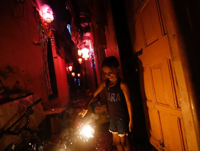 A girl plays with firecracker on the eve of the Hindu festival of Diwali in a slum in Mumbai, October 18, 2017. (Photo by Danish Siddiqui/Reuters)