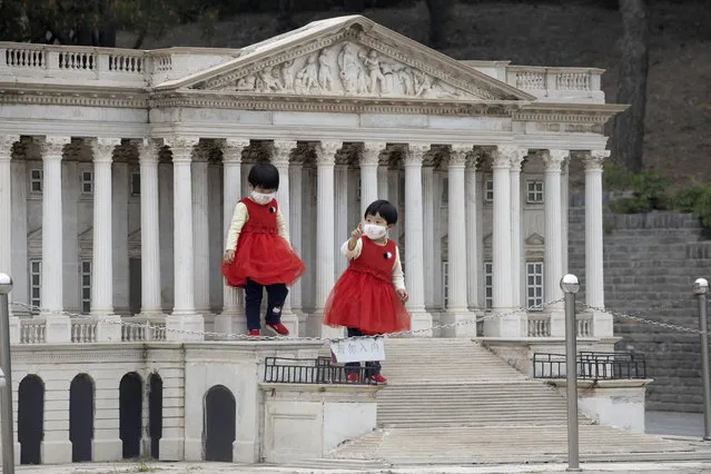 Children wearing face masks stand on the steps of a scaled replica of the United States Capitol Building at the World Park in Beijing on Thursday, May 7, 2020. World tourism has been hard hit by the outbreak of the COVID-19 coronavirus as countries close borders and restricted international flights. (Photo by Ng Han Guan/AP Photo)
