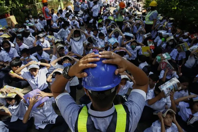 A teacher shows students a protective position during an earthquake drill at an elementary school in Quezon City, Metro Manila, Philippines, 08 September 2022. The Philippines conducted its third quarter nationwide earthquake drill on 08 September, in efforts to enjoin the public to participate in the exercises to improve response protocols during times of disaster. (Photo by Rolex Dela Pena/EPA/EFE)