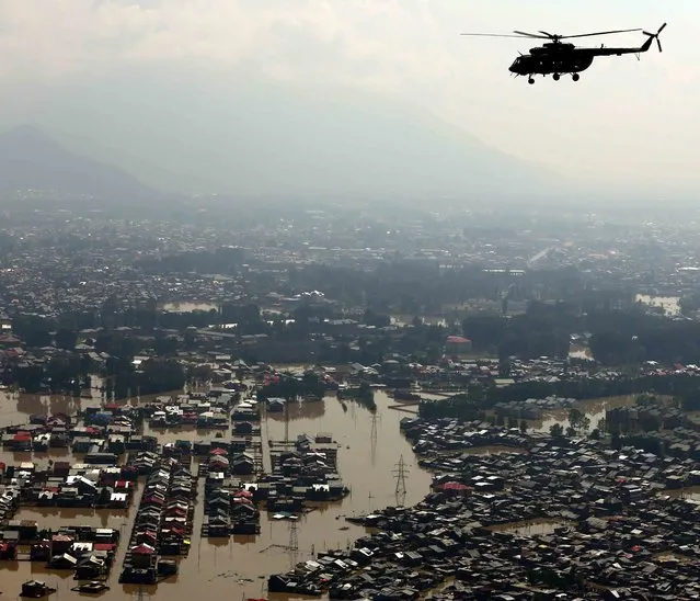 In this handout photograph released by the Ministry of Defence on September 13, 2014, An Indian Air Force Mi-17 flies over floodwaters during a rescue and relief mission over Srinagar. Rescuers struggled to reach more than 200,000 people still stranded in Indian Kashmir as deadly floodwaters receded, revealing horrific devastation in the Himalayan region including neighbouring Pakistan, officials said. (Photo by Vijay Kumar/AFP Photo/Ministry of Defence)