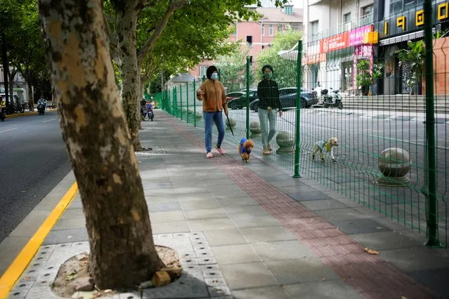 Women with dogs chat through gaps in a barrier at a sealed area, following the coronavirus outbreak, in Shanghai, China on October 11, 2022. (Photo by Aly Song/Reuters)