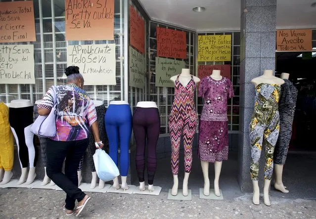 A woman walks past clothes for sale and signs reading “Closing down sale” in Arecibo, Puerto Rico, June 29, 2015. (Photo by Alvin Baez-Hernandez/Reuters)