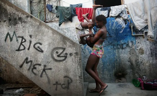 People play in a delapidated section of the occupied Complexo da Mare, one of the largest favela complexes in Rio, on October 10, 2014 in Rio de Janeiro, Brazil. There is one running pipe of water for dozens of residents in the area. The Mare favela is currently occupied by Brazilian military soldiers. Brazilian President and Workers' Party (PT) candidate Dilma Rousseff faces Brazilian Social Democratic Party (PSDB) challenger Aecio Neves in a run-off election on October 26. (Photo by Mario Tama/Getty Images)