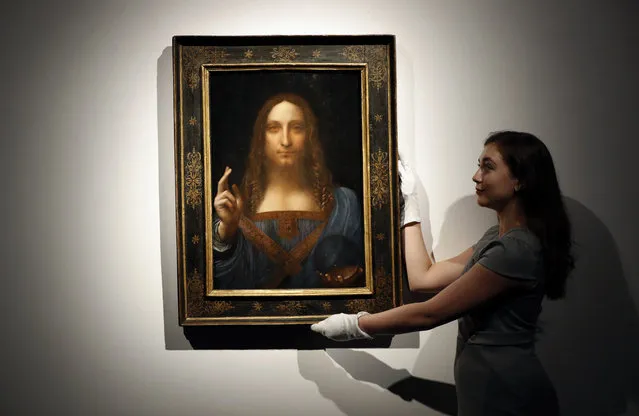 In this October 24, 2017 file photo, an employee poses with Leonardo da Vinci's “Salvator Mundi” on display at Christie's auction rooms in London. The rare painting of Christ, which that sold for a record $450 million, is heading to a museum in Abu Dhabi. The newly-opened Louvre Abu Dhabi made the announcement in a tweet on Wednesday, Dec. 6. (Photo by Kirsty Wigglesworth/AP Photo)
