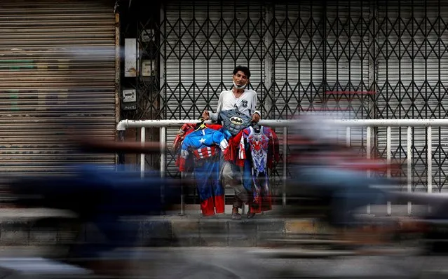 Mohammad Asif, 30, stands as he carries superheroes costumes for children, while selling them along a road, as the markets are closed after Pakistani authorities re-imposed lockdowns in selected areas in an effort to stop the spread of the coronavirus disease (COVID-19), in Karachi, Pakistan, June 25, 2020. (Photo by Akhtar Soomro/Reuters)