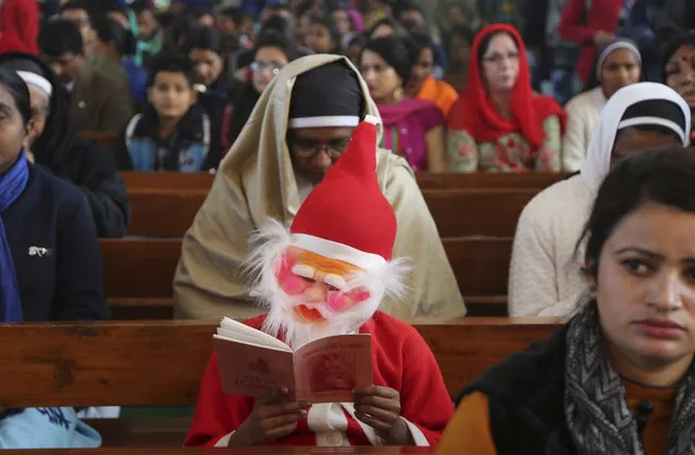 An Indian boy wearing a Santa Claus costume is seated with other worshippers at Saint Mary's Garrison Church on Christmas Day in Jammu, India, Monday, December 25, 2017. (Photo by Channi Anand/AP Photo)