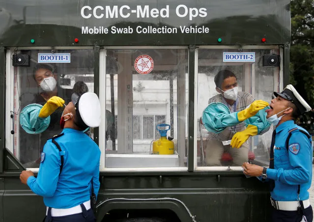 Health officials take a swab sample for the coronavirus disease (COVID-19) from traffic policemen while siting inside a mobile swab collection vehicle at Singha Durbar office complex, that houses the Prime Minister's office and other ministries, in Kathmandu, Nepal on July 29, 2020. (Photo by Navesh Chitrakar/Reuters)