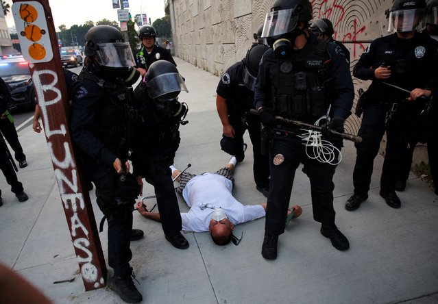 A demonstrator falls while getting detained by the police as protesters gather around the Los Angeles Federal Building following multiple detentions by Immigration and Customs Enforcement (ICE), in downtown Los Angeles, California, U.S., June 6, 2025. (Photo by Daniel Cole/Reuters)