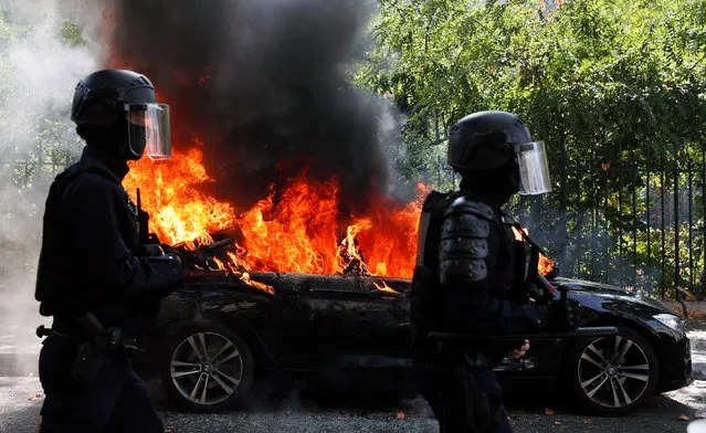 French CRS riot police officers walk past a burning car during a demonstration of the yellow vests movement in Paris, France on September 12, 2020. (Photo by Gonzalo Fuentes/Reuters)