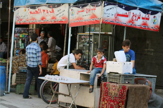 A boy looks on, inside a market in the rebel-held al-Shaar neighbourhood of Aleppo, Syria, September 17, 2016. The sign reads in Arabic: “Hussein's Kebab and chicken”. (Photo by Abdalrhman Ismail/Reuters)