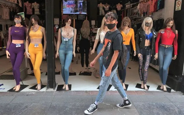 A person wearing face mask walks in front of mannequins who also wear face mask on July 15, 2020 in Mexico City, Mexico. While most of the Mexican States remain in orange color level, some activities considered non essential are now allowed by the government and the “new normal” is gradually assimilated by society. (Photo by Hector Vivas/Getty Images)