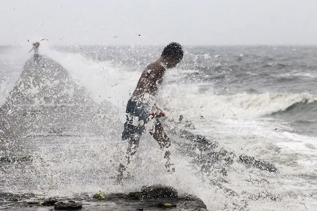 A boy searches for reusable plastic bottles while being pelted by waves brought by typhoon Koppu in Manila Bay October 18, 2015. (Photo by Romeo Ranoco/Reuters)