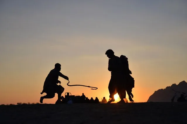 In this photograph taken on January 22, 2023, Afghan men play a traditional rope game 'Dora' along a field in Dand district of Kandahar province. (Photo by Sanaullah Seiam/AFP Photo)