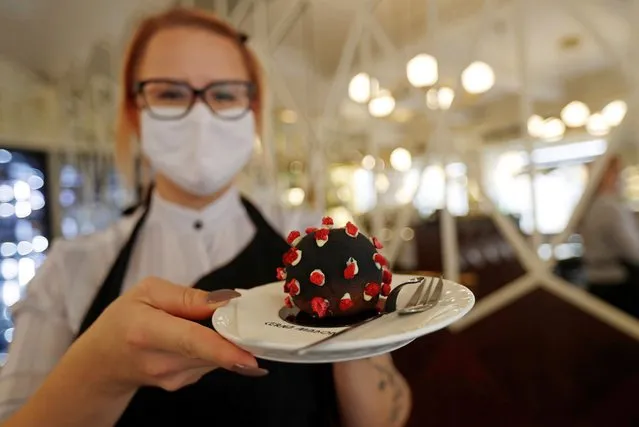 A waitress serves a cake shaped like a microscopic view of the coronavirus SARS-CoV-2, amid concerns about the spread of the disease (COVID-19), at a cafe in Prague, Czech Republic, October 5, 2020. (Photo by David W. Cerny/Reuters)