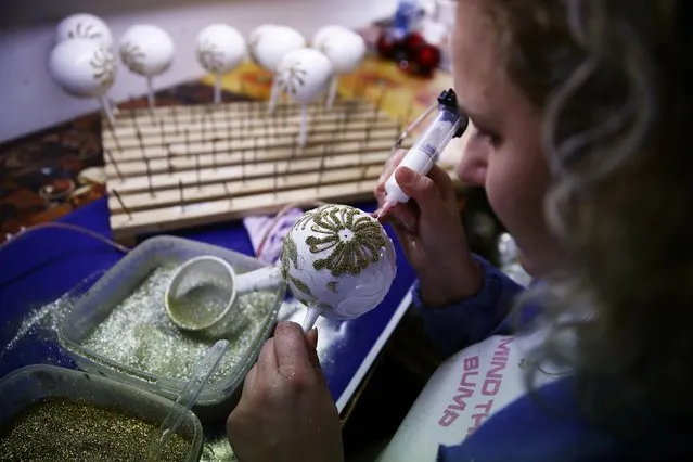 A worker paints Christmas decorations on glass baubles at the Silverado manufacture of hand-blown Christmas ornaments in the town of Jozefow, outside Warsaw December 2, 2014. (Photo by Kacper Pempel/Reuters)