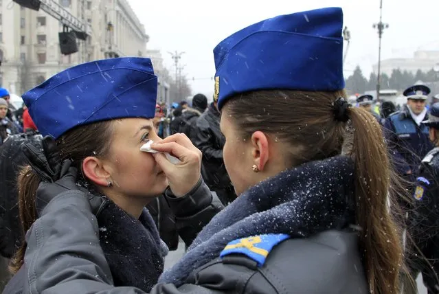 A member of the air force helps her colleague with her make-up before a military parade celebrating Romania's National Day in Bucharest December 1, 2014. (Photo by Radu Sigheti/Reuters)