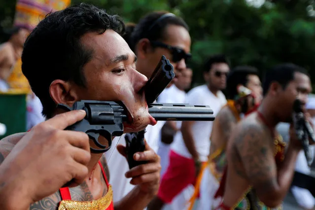 A devotee of the Chinese Samkong Shrine walks with two revolvers pierced in his mouth during a procession celebrating the annual vegetarian festival in Phuket, Thailand Octuber 4, 2016. (Photo by Jorge Silva/Reuters)